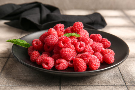Plate with fresh raspberries and mint on gray tile tableの写真素材