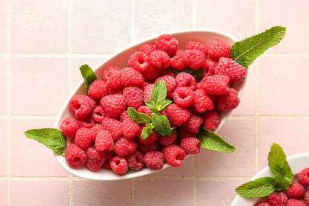 Bowl with fresh raspberries and mint on pink tile backgroundの写真素材
