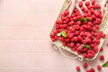 Tray with fresh raspberries and mint on pink tile backgroundの写真素材