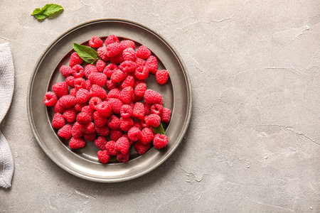 Plate with fresh raspberries and mint on gray backgroundの写真素材