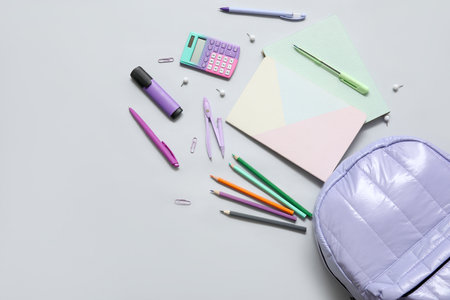 Lilac school backpack with notebooks, calculator and pencils on gray backgroundの写真素材