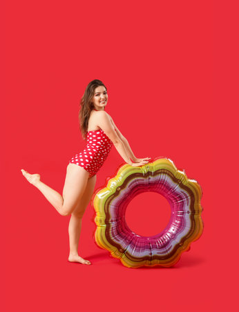Young woman with swim ring on red backgroundの写真素材