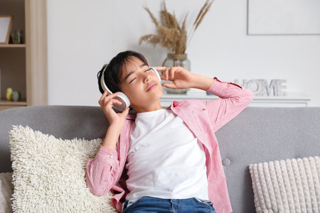 Little boy in headphones listening to music at homeの写真素材