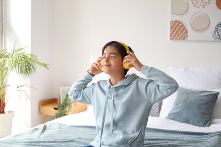 Little boy with headphones listening to music in the bedroomの写真素材