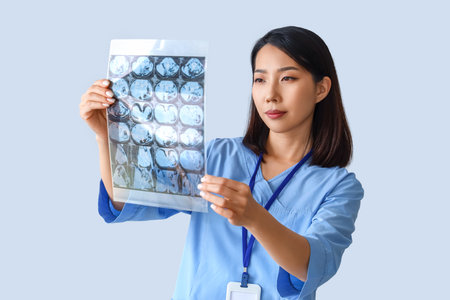 Female Asian medical intern with x-ray scan on gray backgroundの写真素材