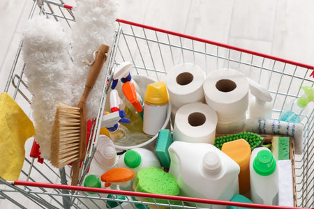 Shopping cart full of cleaning supplies on wooden floorの写真素材