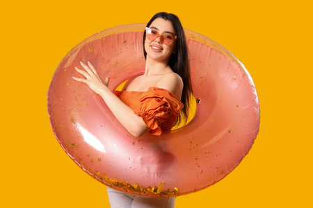 Young woman with pink inflatable ring on orange backgroundの写真素材