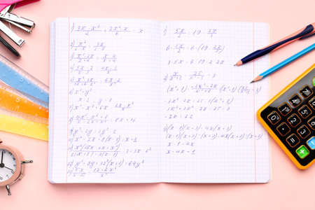 Copybook with maths formulas, calculator and stationery on pink backgroundの写真素材