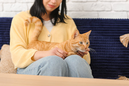 Woman with ginger cat sitting on sofa at home, closeupの写真素材