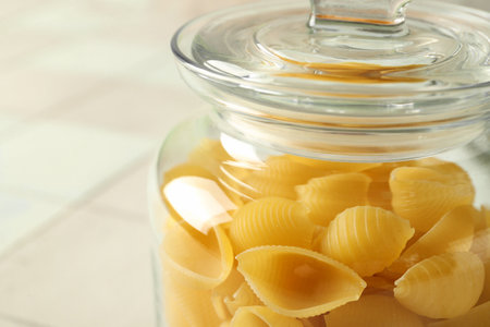 Jar with raw conchiglie pasta on table, closeupの写真素材
