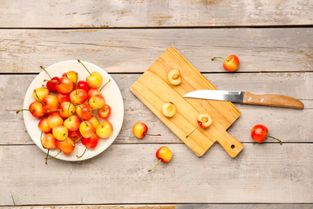Plate and board with sweet yellow cherries on gray wooden backgroundの写真素材