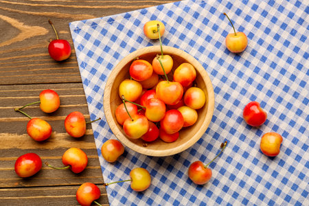 Bowl with sweet yellow cherries on wooden backgroundの写真素材