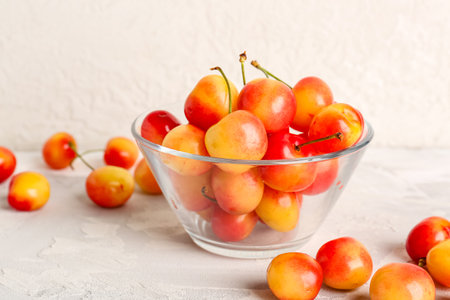 Glass bowl with sweet yellow cherries on white backgroundの写真素材