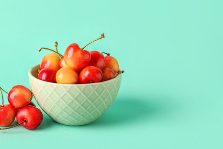 Bowl with sweet yellow cherries on turquoise backgroundの写真素材