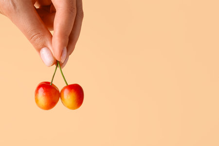 Woman holding sweet yellow cherry on orange backgroundの写真素材