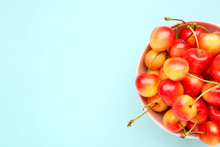 Bowl with sweet yellow cherries on blue backgroundの写真素材