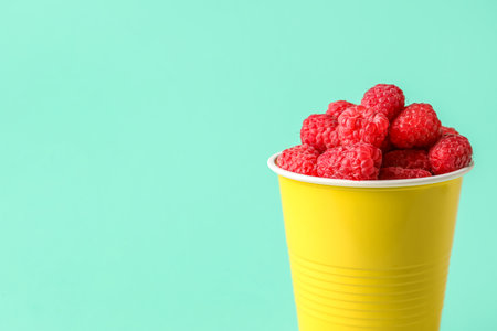 Plastic cup with fresh raspberries on turquoise backgroundの写真素材