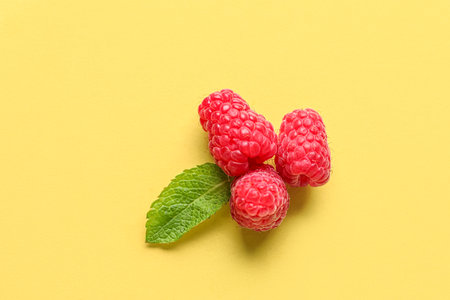 Fresh raspberries and mint on yellow backgroundの写真素材