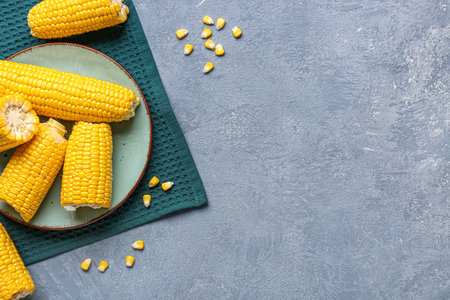 Plate with fresh corn cobs and seeds on blue backgroundの写真素材