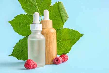 Bottles of cosmetic raspberry oil on blue background