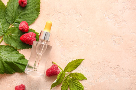 Bottle of cosmetic raspberry oil on pink table