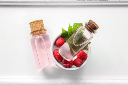 Bottles of cosmetic raspberry oil on white tableの写真素材