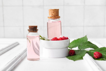 Bottles of cosmetic raspberry oil on white tableの写真素材