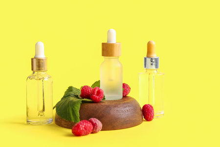 Bottles of cosmetic raspberry oil on yellow backgroundの写真素材