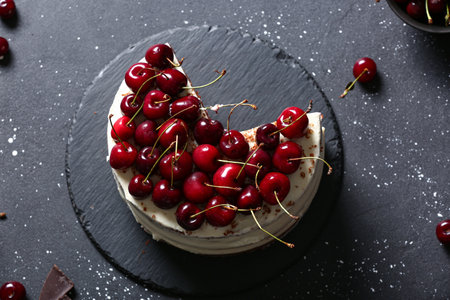 Board with tasty cherry cake on black tableの写真素材