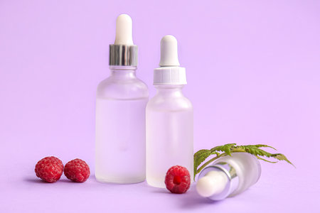 Bottles of cosmetic raspberry oil on lilac backgroundの写真素材