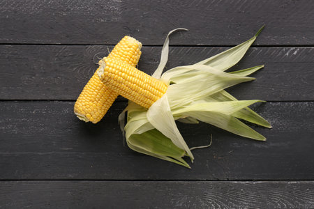 Fresh corn cobs on black wooden backgroundの写真素材