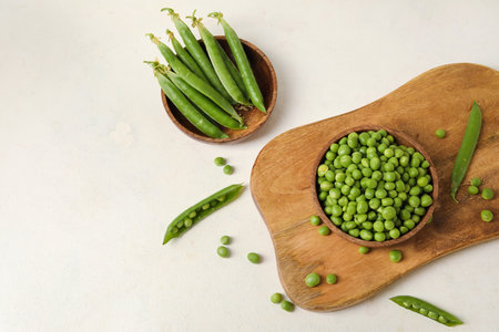 Bowls and wooden board with fresh green peas on white backgroundの写真素材