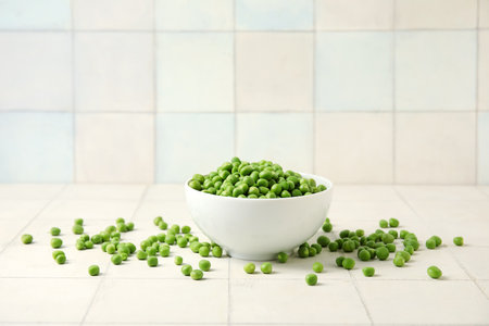 Bowl with fresh green peas on white tile backgroundの写真素材