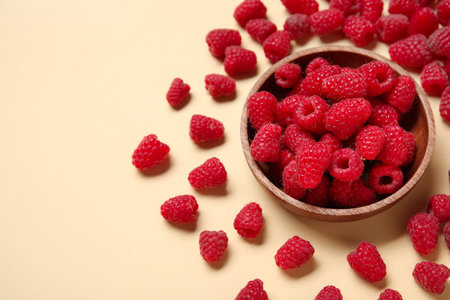 Bowl with fresh raspberries on yellow background