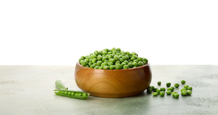 Bowl with fresh green peas on black table against white backgroundの写真素材