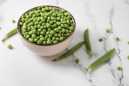 Bowl with fresh green peas on white backgroundの写真素材