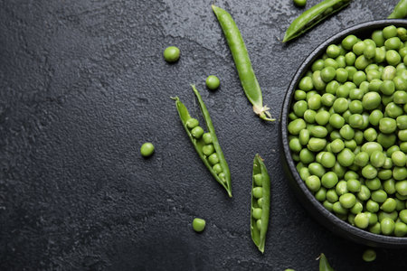 Bowl with fresh green peas on black backgroundの写真素材