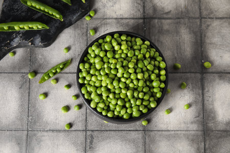 Bowl and board with fresh green peas on gray tile tableの写真素材
