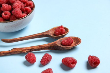 Bowl and spoons with fresh raspberries on blue backgroundの写真素材