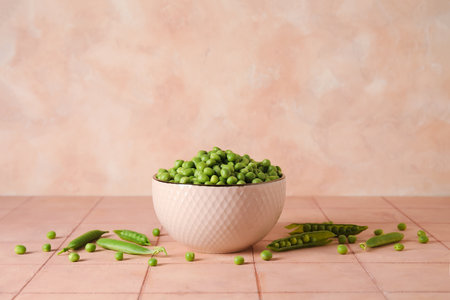 Bowl with fresh green peas on pink tile tableの写真素材