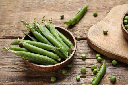 Bowl with fresh green peas on wooden backgroundの写真素材