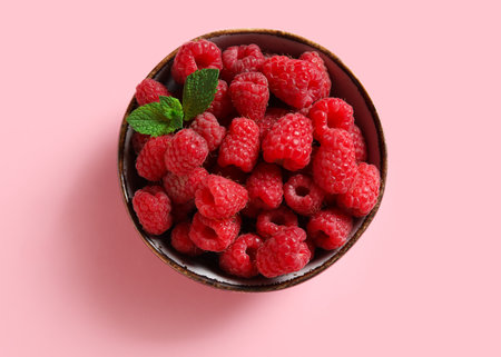 Bowl with fresh raspberries and mint on pink backgroundの写真素材
