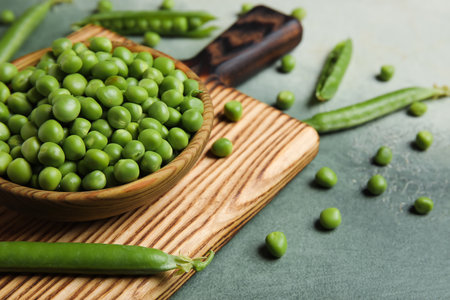 Bowl and wooden board with fresh green peas on grunge backgroundの写真素材