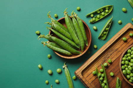 Bowl and wooden board with fresh green peas on color backgroundの写真素材