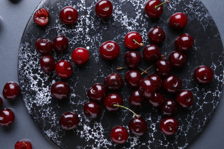 Board with sweet cherry on gray backgroundの写真素材
