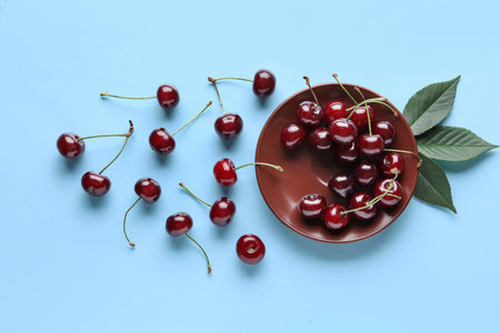 Plate with sweet cherry and leaves on blue backgroundの写真素材