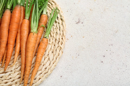 Fresh carrots and wicker mat on white grunge backgroundの写真素材