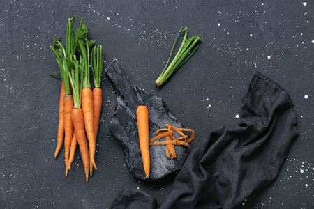 Fresh carrots and wooden board on black grunge backgroundの写真素材
