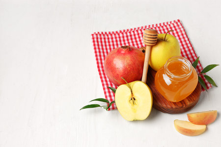Board with jar of honey, pomegranate and apples for Rosh Hashanah celebration (Jewish New Year) on white wooden backgroundの写真素材