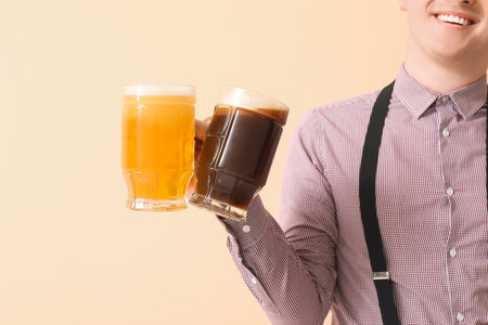 Young man in traditional German clothes with beer on beige background, closeupの写真素材